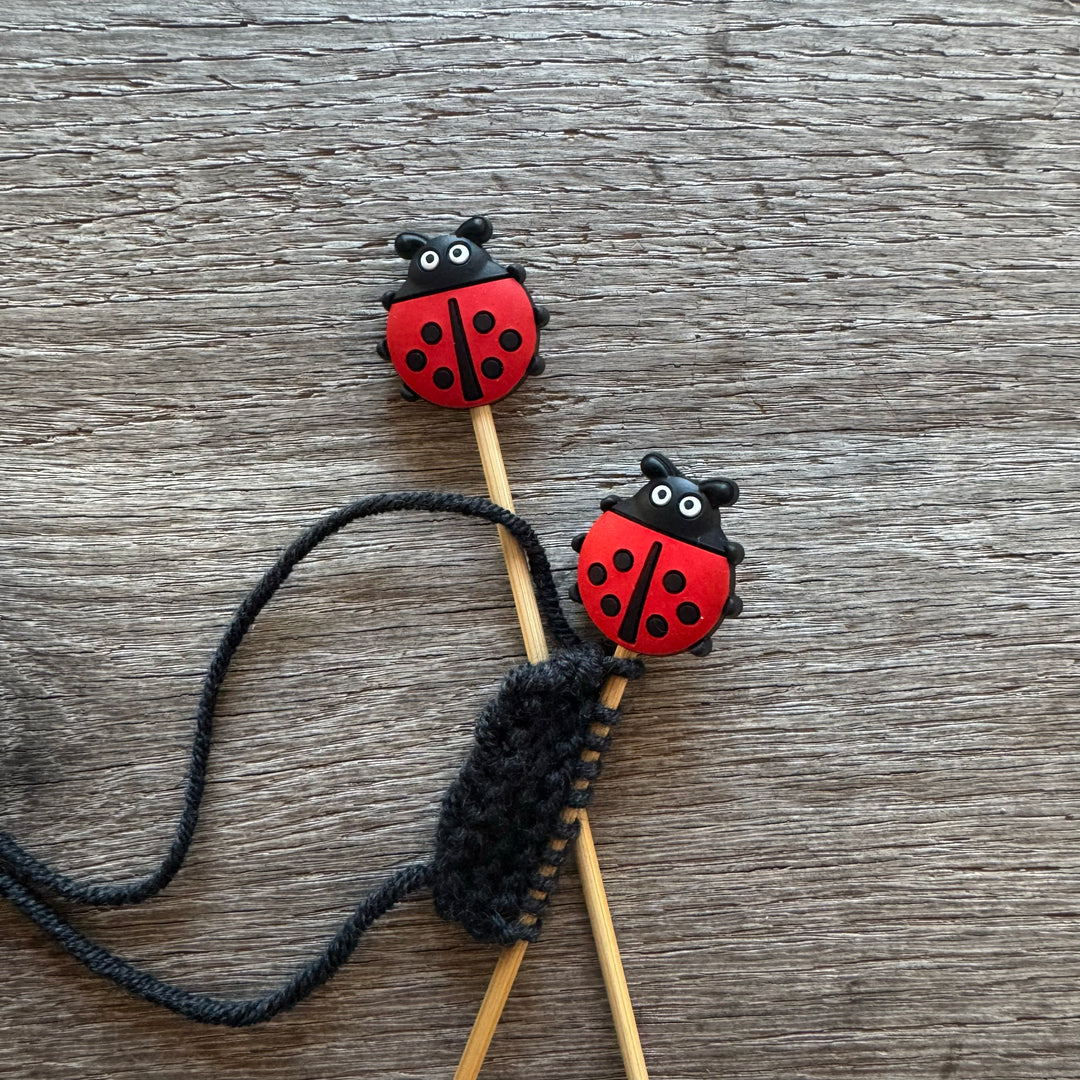 Knitting needles with ladybug-shaped ends on a wooden surface