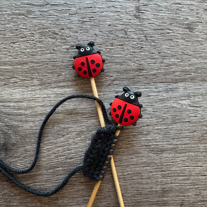 Knitting needles with ladybug-shaped ends on a wooden surface
